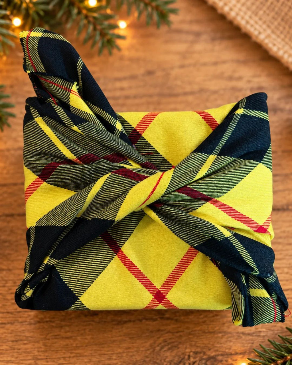 Emballage cadeau réutilisable en tissu tartan jaune, noir et rouge, noué style furoshiki. Emballage cadeau écologique fait à la main au Québec.
