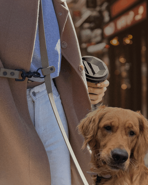 Laisse pour chien mains libres portée à la taille avec un café à la main